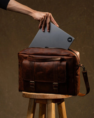 Deri laptop çantasına laptop yerleştiren el